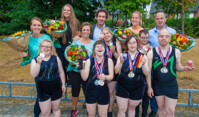 De trotse turners met medailles en de wethouder.