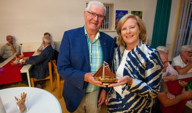 Wethouder Marlous Verbeek schenkt waarnemend voorzitter Henk Brasser een klein bottertje.