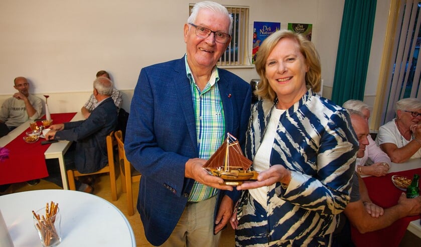 Wethouder Marlous Verbeek schenkt waarnemend voorzitter Henk Brasser een klein bottertje.