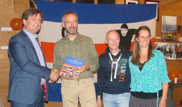 Wethouder Floris Voorink (links) neemt het eerste exemplaar van het jubileumboek in ontvangst uit handen van Marinus Kamphorst vergezeld door medecommissieleden Wim Dral en Anneleen Post.