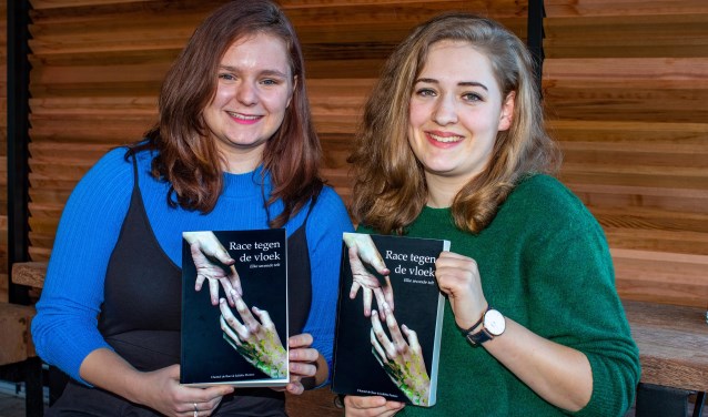 Chantal de Boer (l) en Juliëtte Peeters met hun debuutroman 'Race tegen de Vloek'.