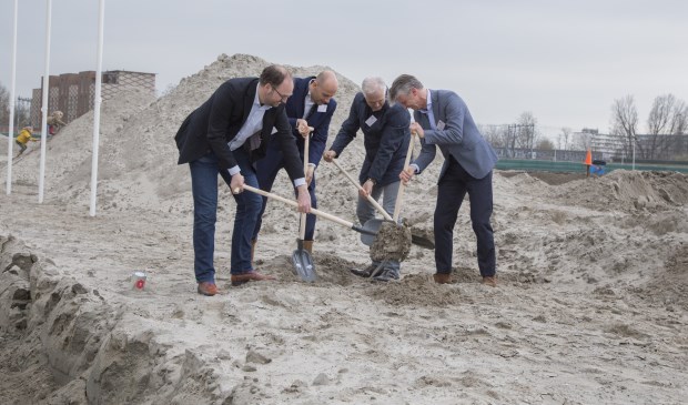 Wethouder Leon de Lange (links) helpt bij het begraven van een tijdcapsule.