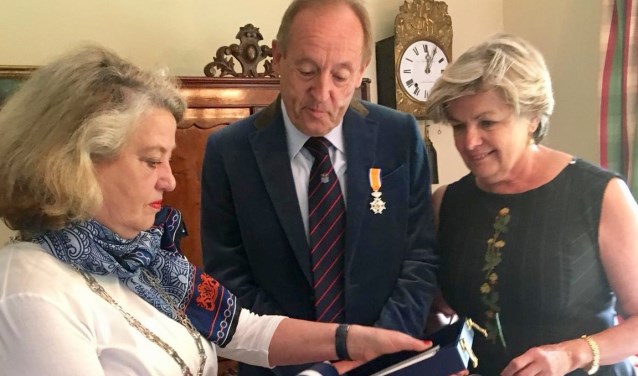 De burgemeester toont het echtpaar Van den Brink alle toebehoren bij de onderscheiding.