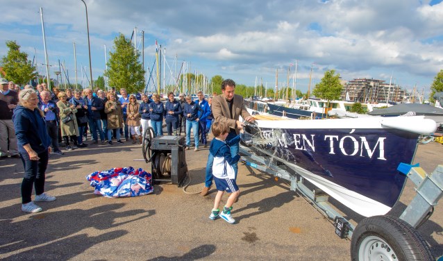 Wethouder Roland Boom doopt de boot met wat hulp. Links voorzitter Erica de Vries.