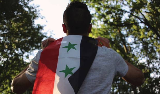 Een man met de vlag van Syrië.