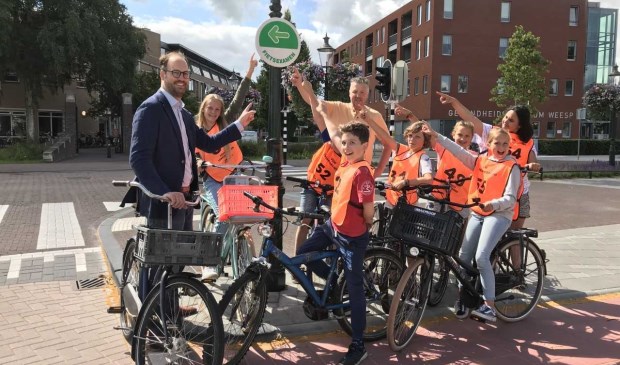 Verkeerswethouder Léon de Lange en fietsexamenkandidaten bij een routebordje.