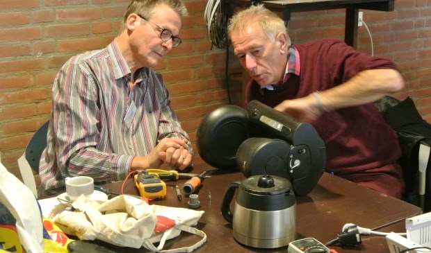 Henk Zandvliet (rechts) onderzocht zijn koffiezetter met behulp van reparateur Peter. Er bleek slechts een nieuwe zekering nodig om het apparaat weer te laten werken.