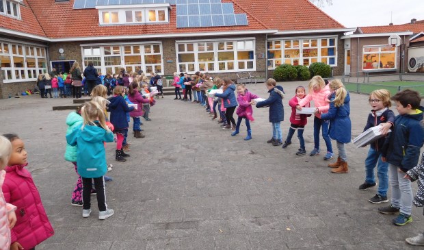 Kinderen van de Groen van Prinstererschool geven de gevulde dozen door op weg naar kinderen die het veel minder hebben.