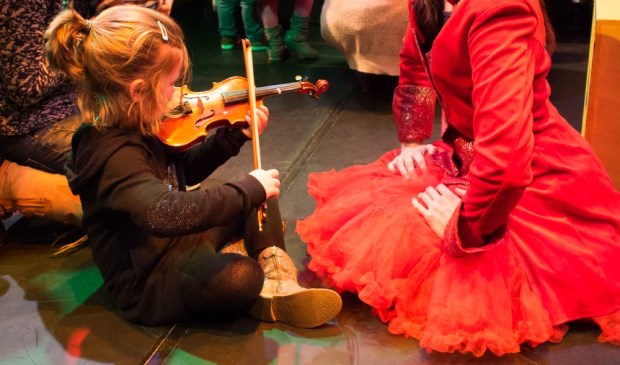 De kinderen worden uitgenodigd om dicht bij de muzikanten en de instrumenten te komen.