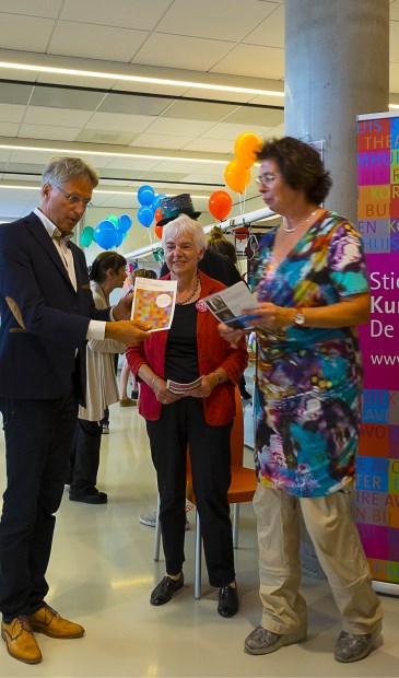 Wethouder Hans Mieras krijgt uit handen van (v.l.n.r. Ellen Thier en Joke Lith het SKC-programma 2017-2018 uitgereikt. (foto Kees van Gogh)