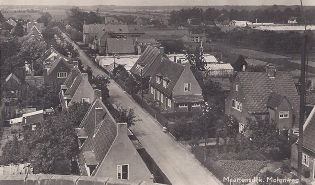 Deze foto van de Maartensdijkse Molenweg is genomen vanaf molen De Hoop en toont de in 1922 gebouwde 10 huizen voor mensen met 'huwelijksvoorrang'. Verder zijn de kassen van van der Heijden en de School met den Bijbel zichtbaar.