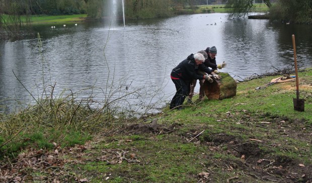 Vrijwilligers brengen de restanten van een omgewaaide boom op het droge.