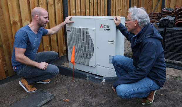 Energieambassadeur Frans den Braber (r) en bewoner Bram de Deugd (l) bekijken de buitenunit van de warmtepomp bij de energieneutrale woning aan de Waterweg in De Bilt. (foto: Jenny Senhorst)