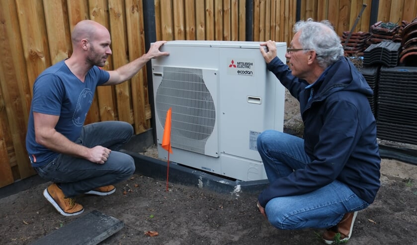 Energieambassadeur Frans den Braber (r) en bewoner Bram de Deugd (l) bekijken de buitenunit van de warmtepomp bij de energieneutrale woning aan de Waterweg in De Bilt. (foto: Jenny Senhorst)