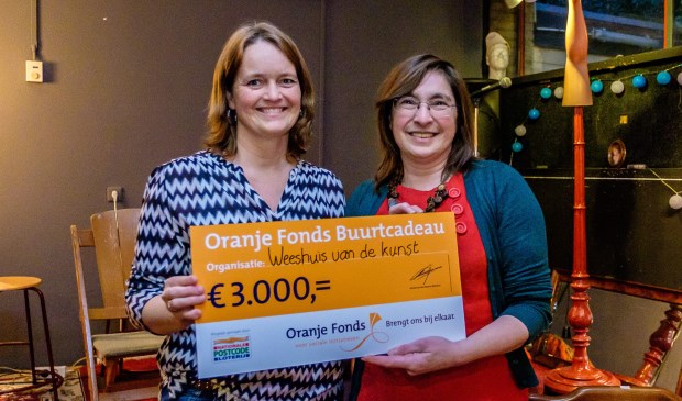 Marinka Peerdemann (l) overhandigt het Buurtcadeau aan Pauline Wijnen.
