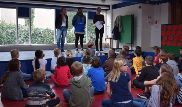 De kids luisteren aandachtig naar buurtsportcoaches Kelly, Soufiane en Fleur.