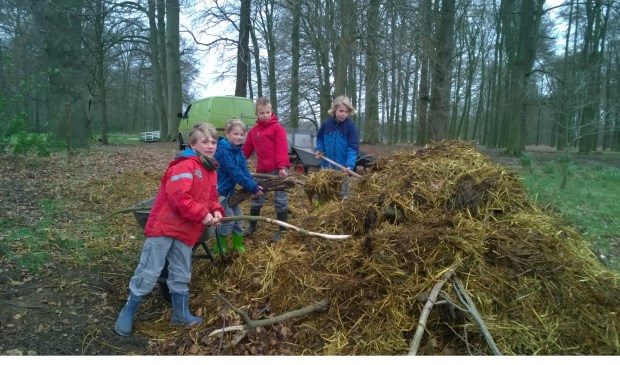 Kinderen zijn druk in de weer met de broeihoop.
