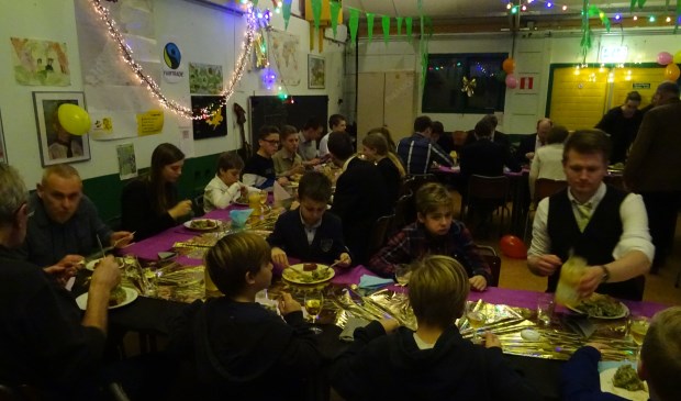 Iedereen geniet van de heerlijke boerenkoolmaaltijd in het feestelijk versierde scoutinggebouw.