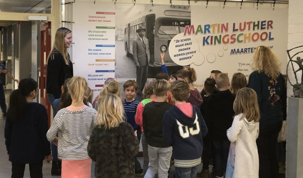Groep 4 krijgt uitleg bij de banner in de school.