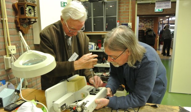 Jan Vinke repareert, samen met de eigenaar, een naaimachine. ( Foto Frans Poot)