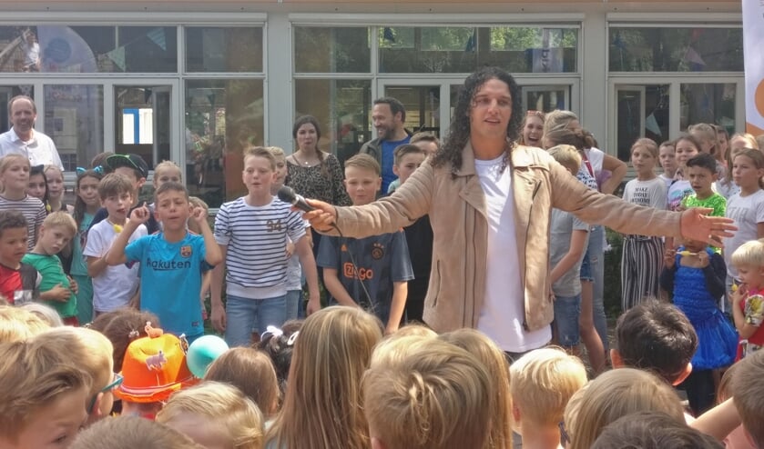 Ali B wordt door de MLK-leerlingen omringd op het schoolplein.