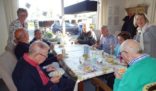 • Begeleiders Anja, Henk en vrijwilligster Jeanette genieten samen met de ouderen van een feestelijke traktatie.