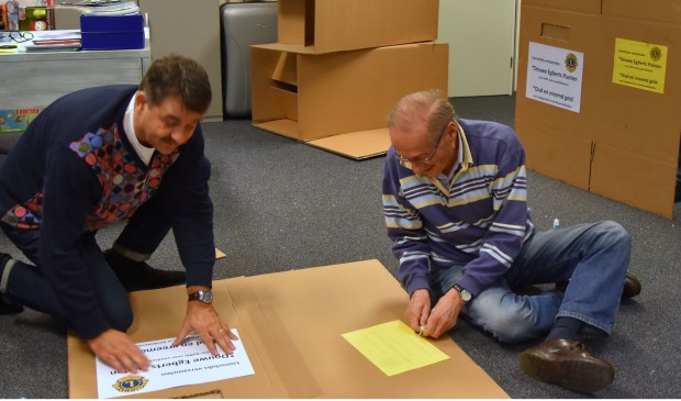 • Leden van Lions Club Krimpen bezig met het vervaardigen van de inzameldozen.