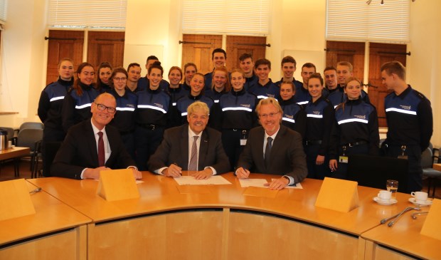 • De ondertekening van de overeenkomst met op de achtergrond de handhavers in opleiding.