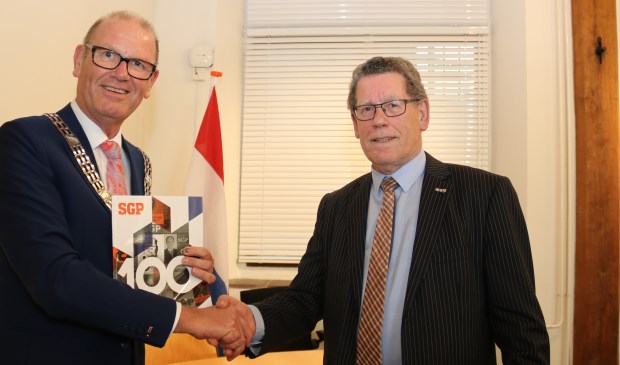 • • Het eerste exemplaar van de SGP-glossy werd uitgereikt aan burgemeester Wim Groeneweg.