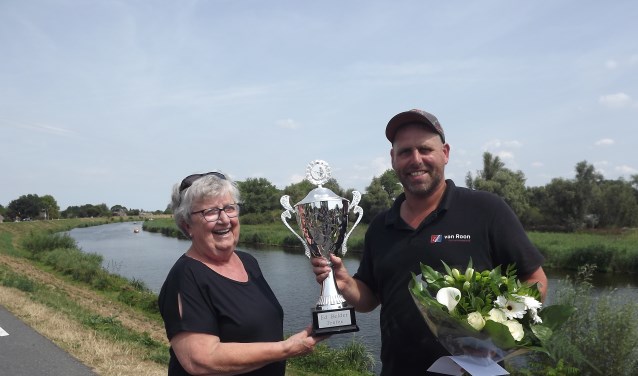 • Elly Belder overhandigt de trofee aan Colin Kooyman.