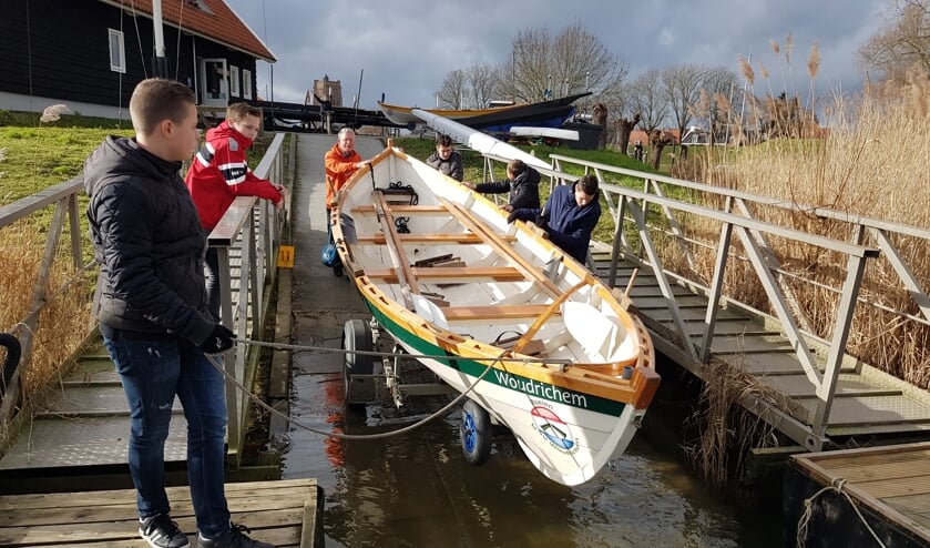 De leerlingen laten samen met Goof van Vliet een St. Ayles Skiff te water.