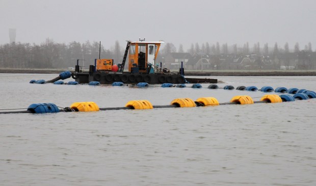 • Het zand voor de bodem gaat via pijpen naar een bootje. Van daaruit wordt het geleidelijk in de surfplas gesproeid.