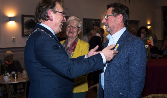 • Burgemeester Keereweer speldt de Koninklijke Onderscheiding op.