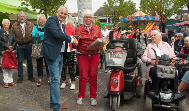 • Wethouder Leon de Wit deelt een prijs van de superloterij uit.