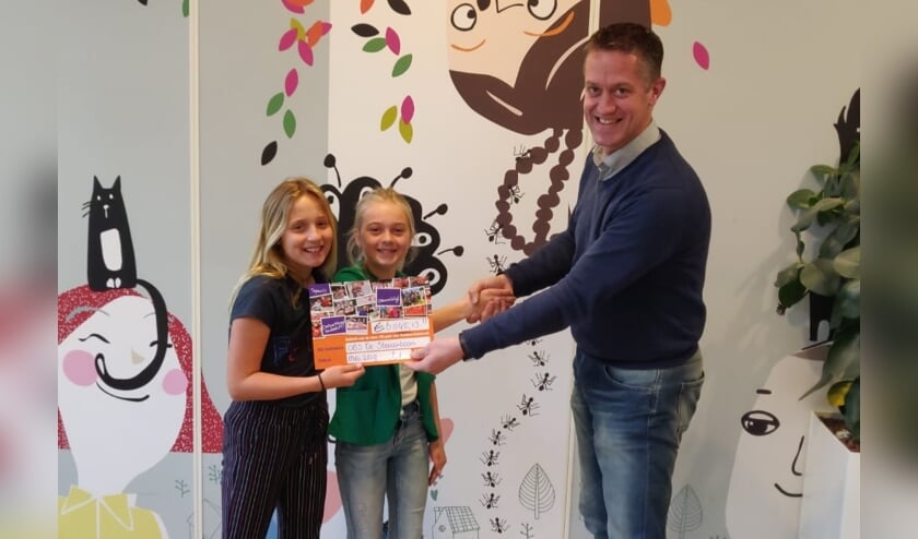 • Interim-directeur Rogier Levy overhandigt de cheque aan de initiatiefneemsters van de sponsorloop, Roos en Sophie.