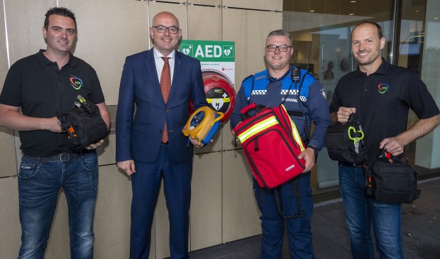 • V.l.n.r.: Marcel Beekman (IOV), Burgemeester Vroom, BOA Xander en Mark Schileroord (IOV). BOA Xander neemt de AED en trauma- en EHBO-pakket in ontvangst.