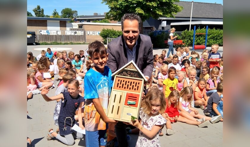 Rutger van Stappershoef overhandigt het insectenhotel aan de jongste en oudste leerling van CBS Het Kompas.