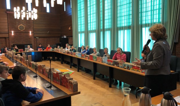 Hoe werkt de politiek en democratie in Nederland? Dat legde burgemeester Bouvy-Koene uit in de raadszaal tijdens een les aan leerlingen van groep 7 en 9. Foto: gemeente Voorschoten