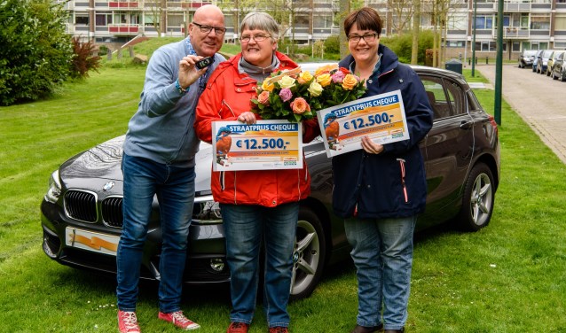 Elly uit Leidschendam wordt, in aanwezigheid van haar dochter Judith, verrast door Postcode Loterij-ambassadeur Gaston Starreveld met de PostcodeStraatprijs-cheque en een BMW (foto: Roy Beusker Fotografie).
