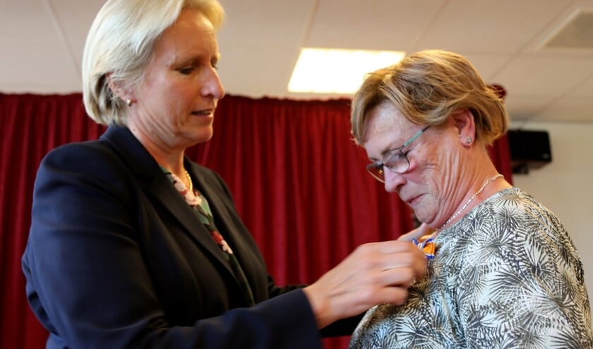 Mendy van Veen speldt de koninklijke onderscheiding op bij Jacqueline van den Akker. (foto's Astrid Abbing)