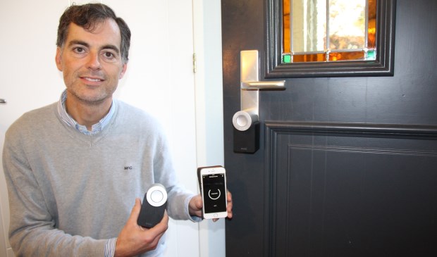 Ewout Hennipman laat zien hoe eenvoudig het is: een App op je telefoon en een apparaatje dat op je bestaande slot de cilinder in je slot naar links of naar rechts draait.
