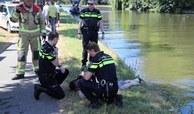 Het slachtoffer ligt bij te komen nadat hij op de kant is geholpen (foto: Rene Hendriks/Regio15).