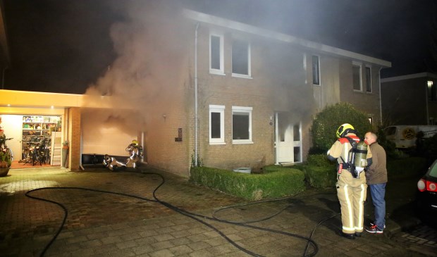 Rookwolken komen uit de garage en het woonhuis, als gevolg van een brand in de garage door een oververhitte schoorsteen van een gaskachtel (foto: Roy Wolters / Regio 15).