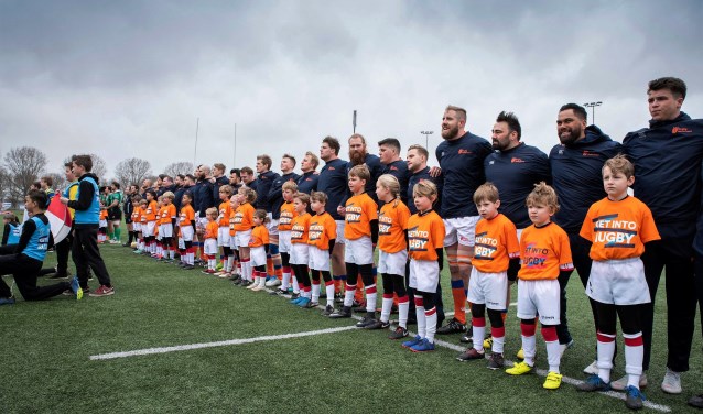 De jeugdleden als player escorts bij de rugbyspelers van het Nederlandse en het Portugese rugyteam (foto: pr VRC).