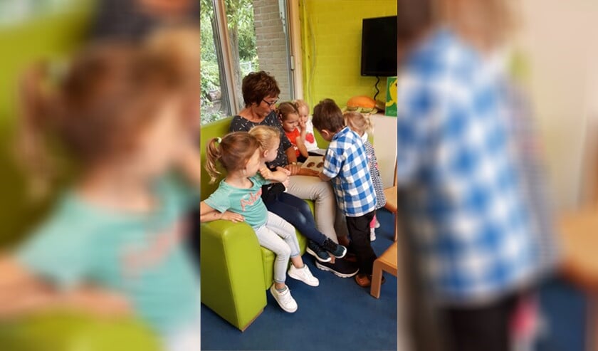 Gerda met een voorleesboek en peuters rondom; een feest voor peuter en juf.
