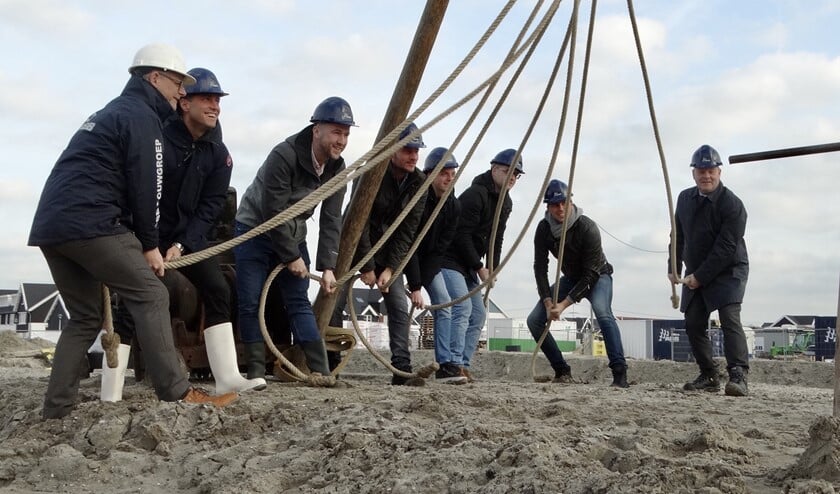 Met vereende krachten wordt de eerste paal geslagen. Geheel rechts wethouder Frank van Kuppeveld.
