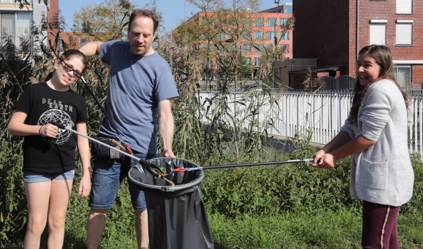 Enthousiaste 'vuilprikkers' aan de slag op zaterdag 19 september aan de Baaklaan in Leidschenveen: Wayra met haar vader en Moya (v.l.n.r.). Foto: Jan van Es