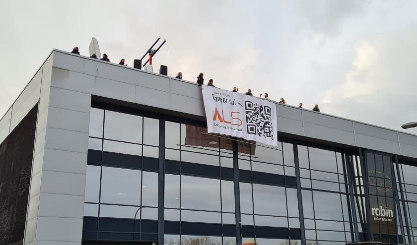 <p>Het moment van tijdelijk uitrollen op donderdag. De banner is vanwege het stormachtige weer weggehaald, maar gaat deze week met een hoogwerker omhoog. Foto: pr </p>