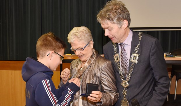 De draagspeld behorende bij de Bronzen Waarderingspenning wordt opgespeld door haar kleinzoon. Foto Hoedemaekers Venray