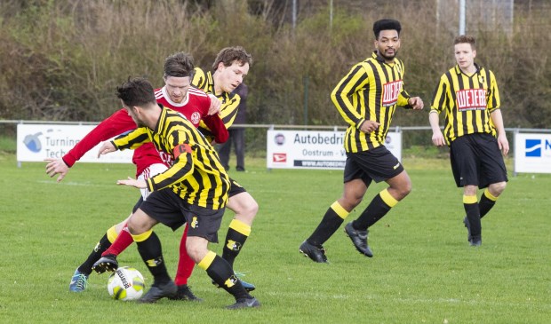 SV Oostrum-aanvaller Chris Wilschut (rood shirt) probeert twee spelers van BVV'27 af te schudden.